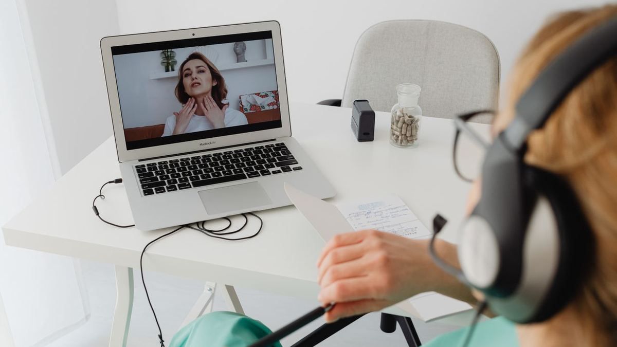 Person wearing headphones on a video coaching call at a laptop