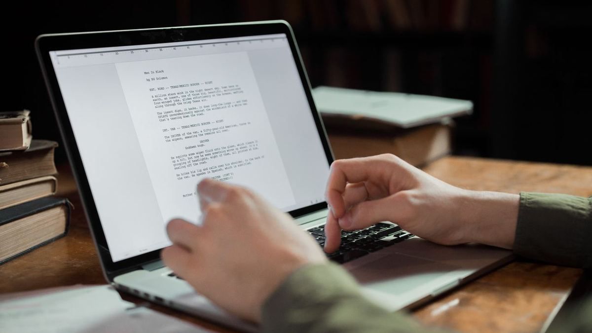 Hands typing a script on a laptop keyboard